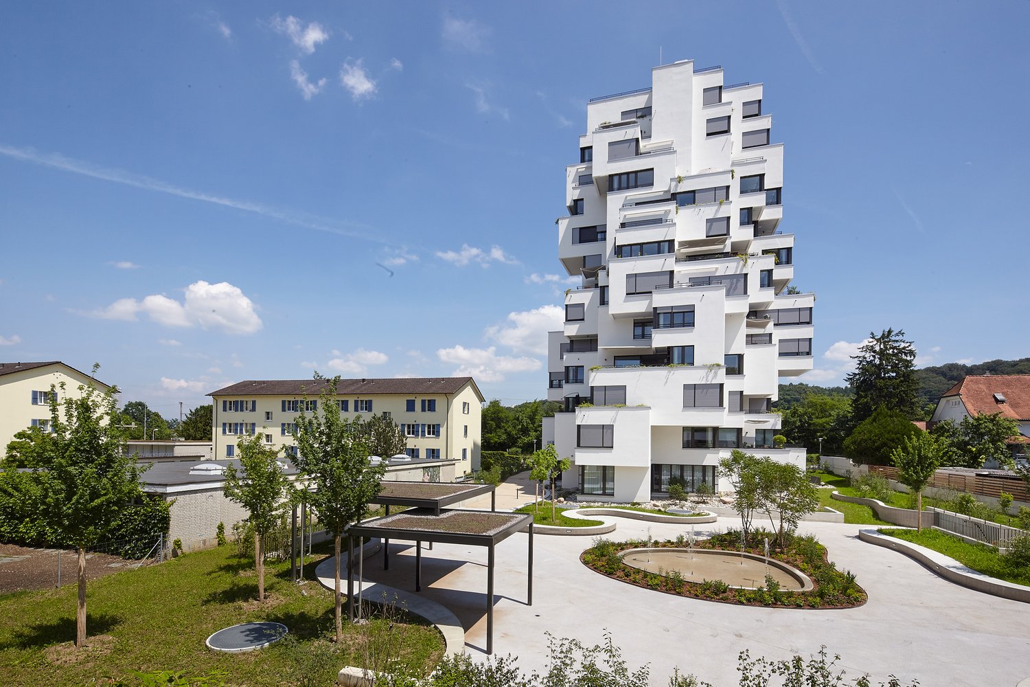 White multistory residential building with balconies and raised ground floor