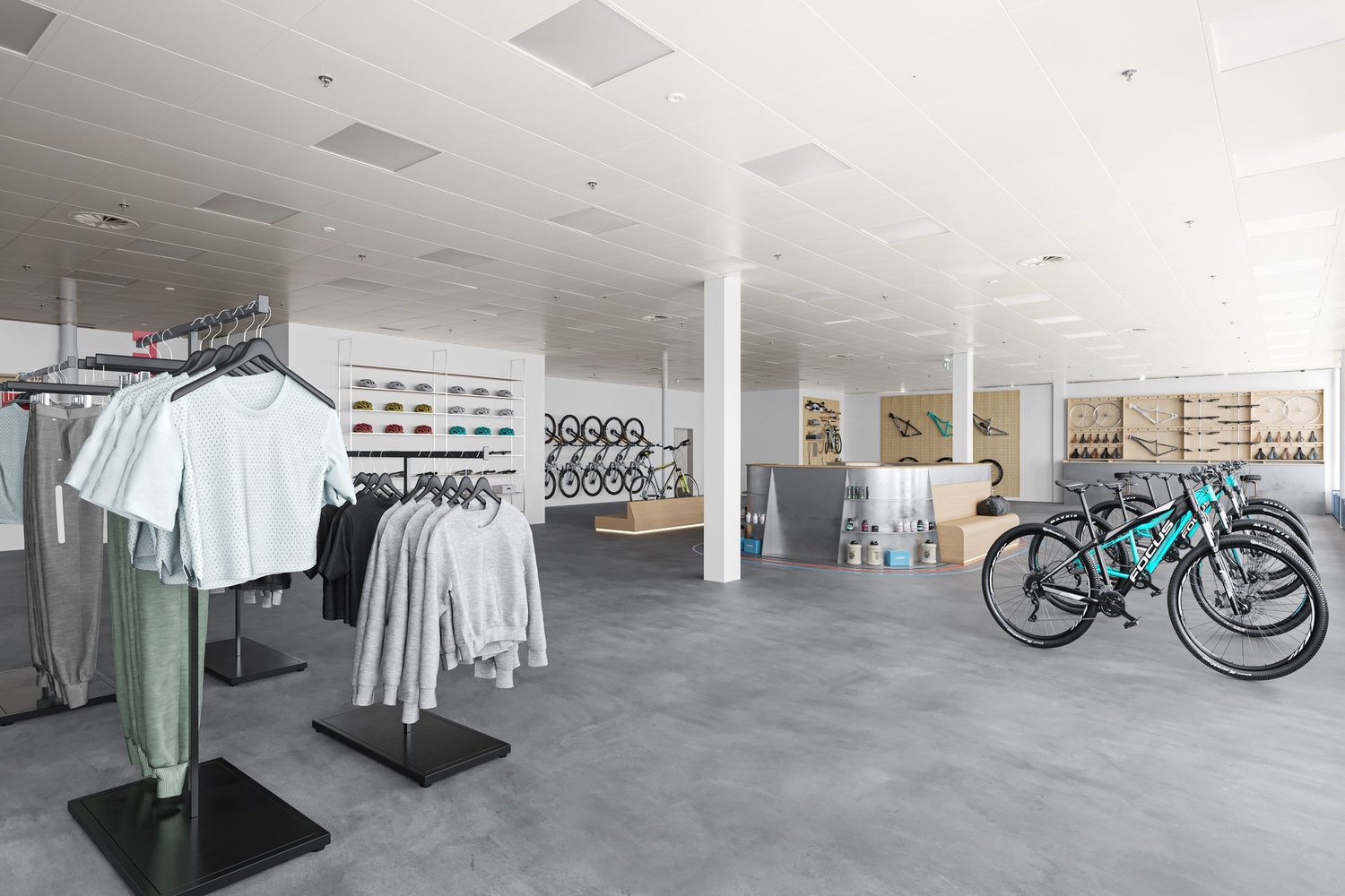 Large open space with clothing racks, shelves displaying accessories, and bicycles on display. The space has a modern, minimalist design with white walls, gray flooring, and recessed lighting.