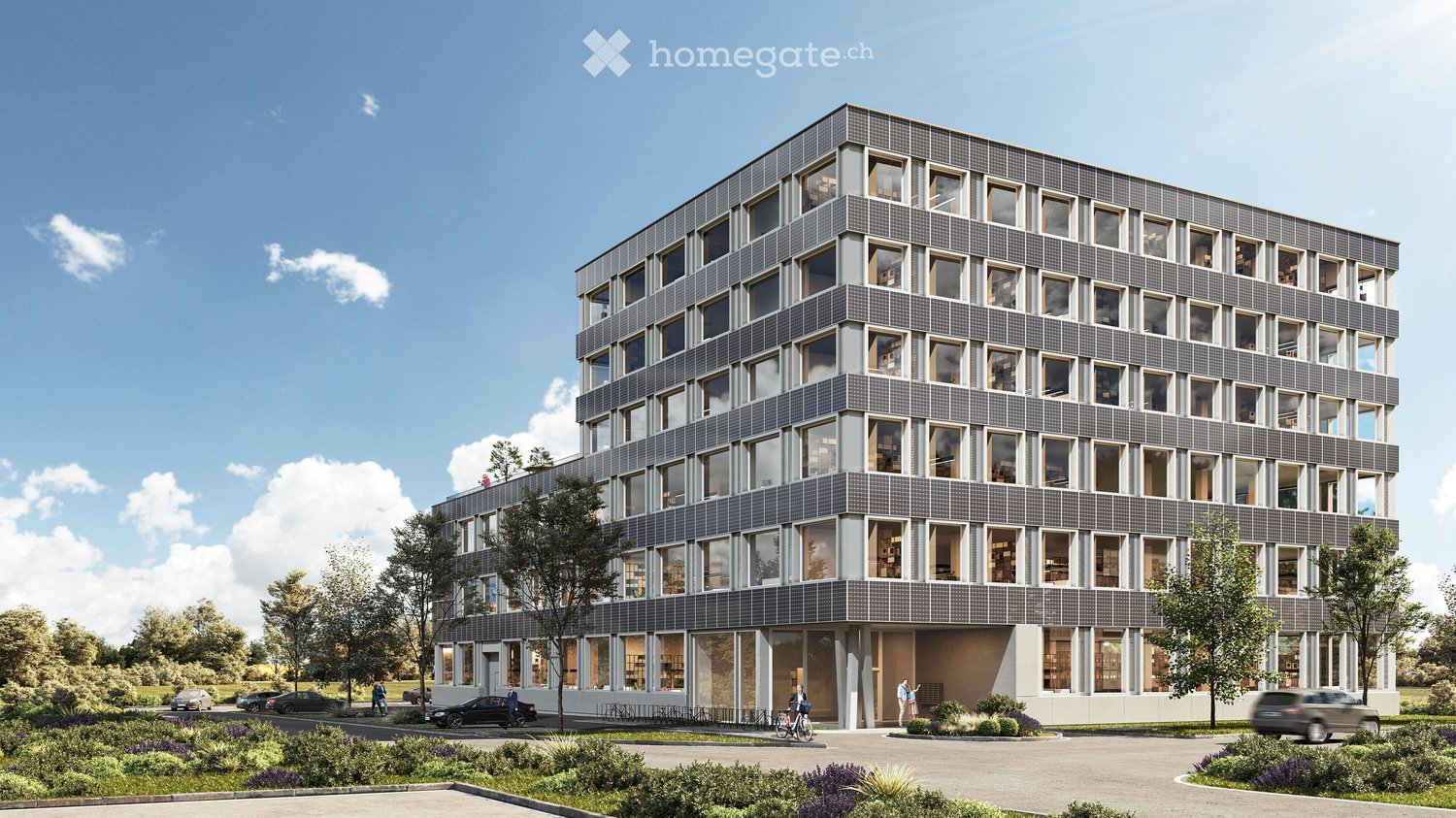 Multi-story office building with a modern, grid-like facade. The building has numerous windows and appears to be surrounded by landscaping, including trees and plants. There is a parking area visible in front of the building.