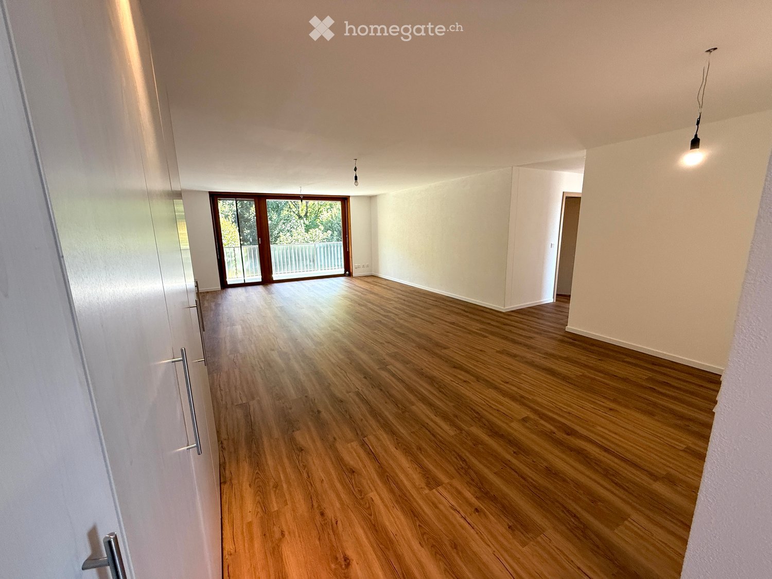 large windows, wooden floor, sliding glass door, balcony, white walls, bright lighting