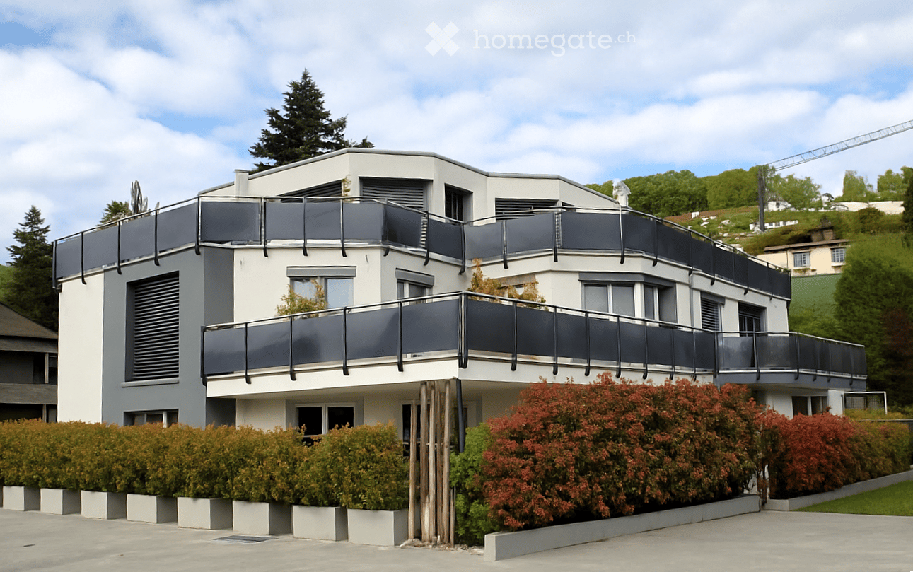Modern white house, multiple windows, large balconies, landscaped front area, small garden