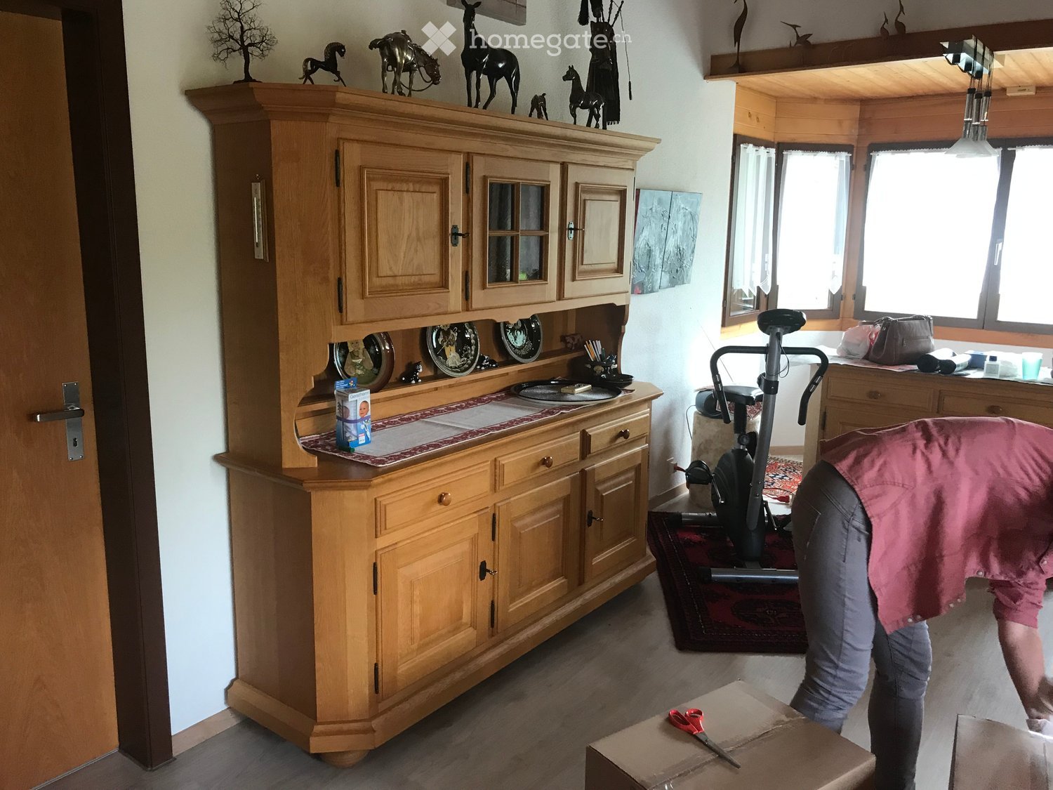 kitchen area with wooden cabinet, plates on top, scissor on open box