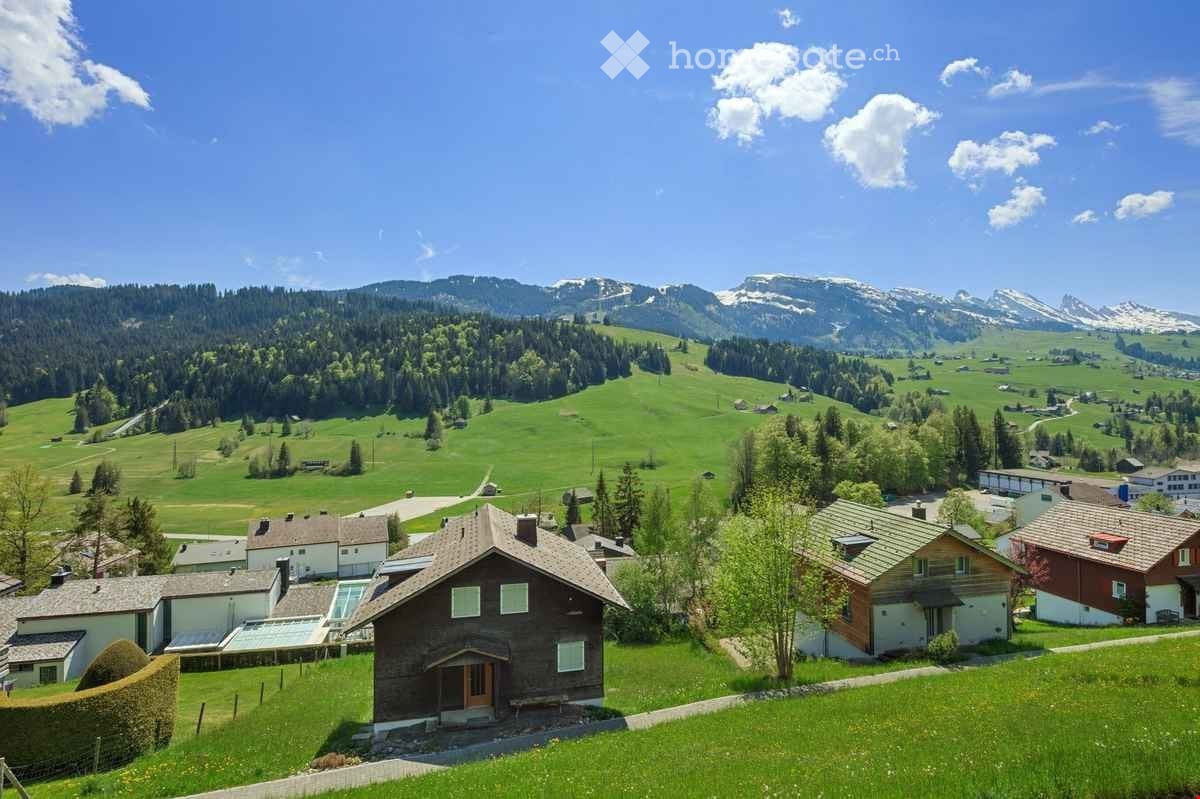 Cluster of houses in a green valley with a view of mountains