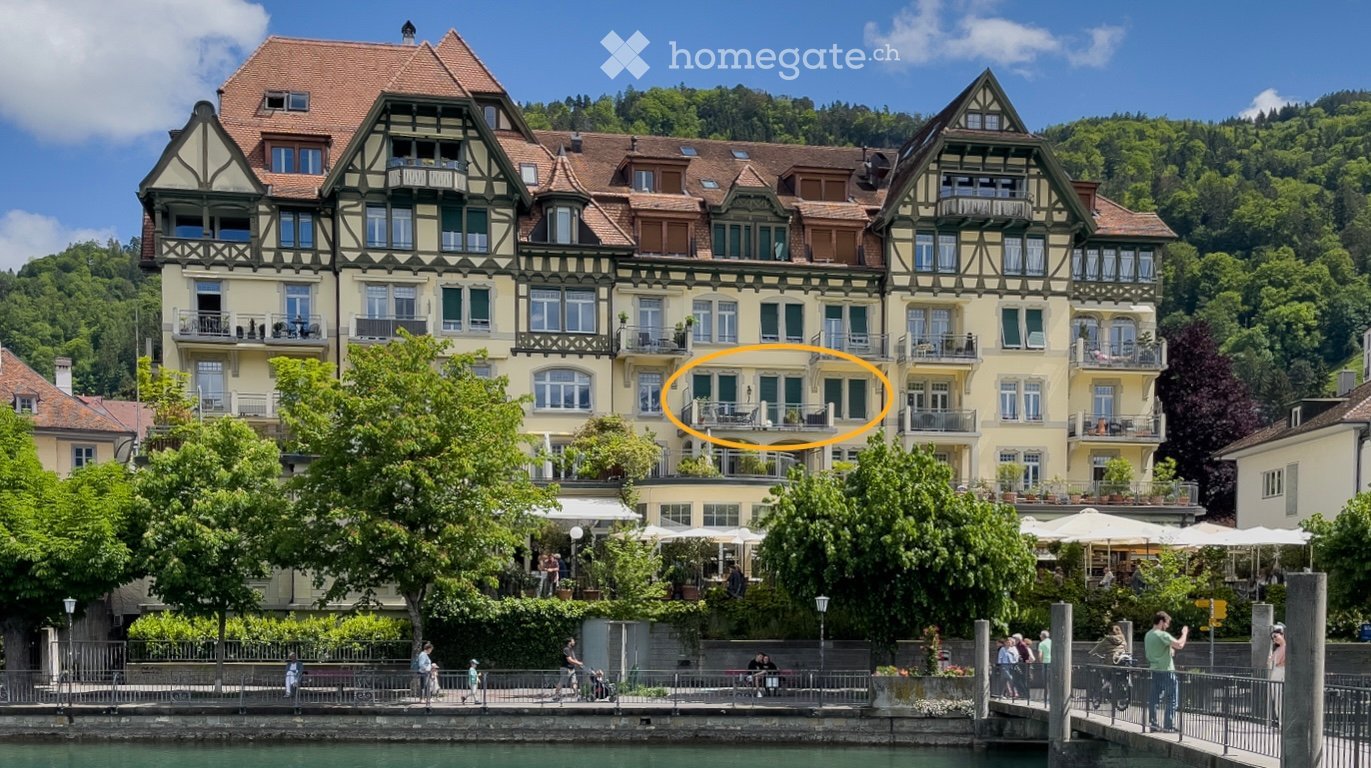 A large building with multiple balconies, many windows, and located near a river.