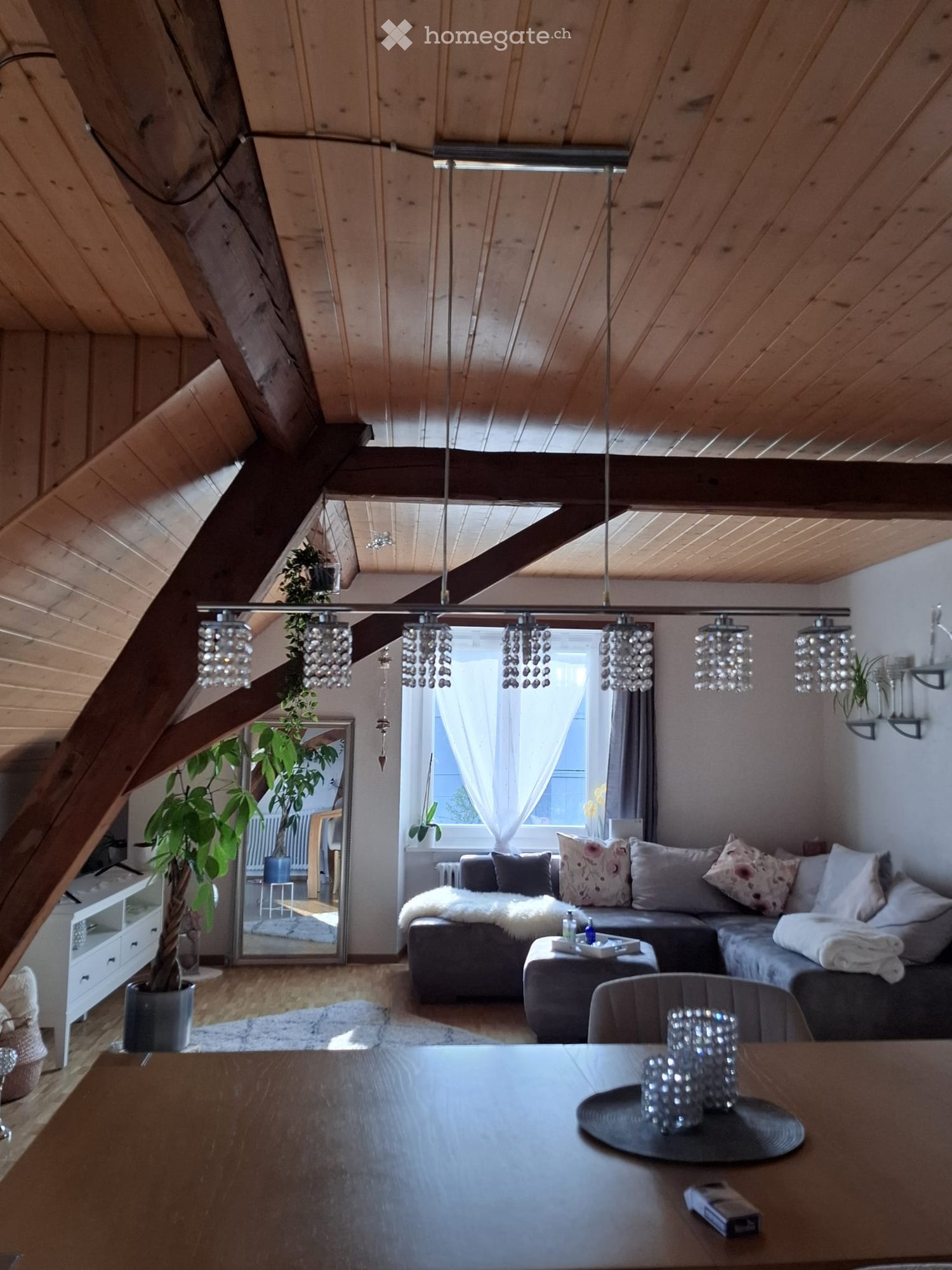 high ceiling, wooden beams, couch, pillow, dining table, crystal chandeliers