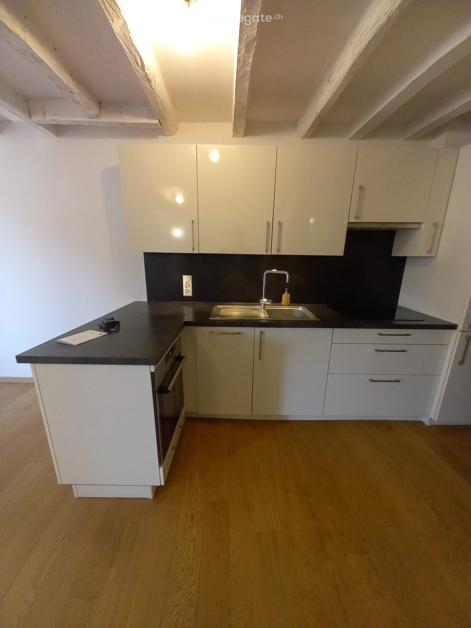 modern kitchen with white cabinets, black countertops, stainless steel sink and oven, wooden floors