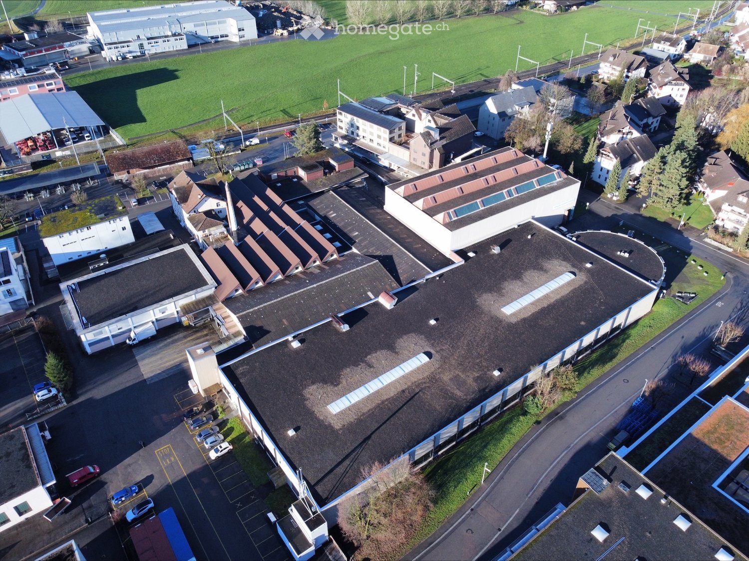 Industrial building with multiple levels, several car parking areas, and a wide area of grass