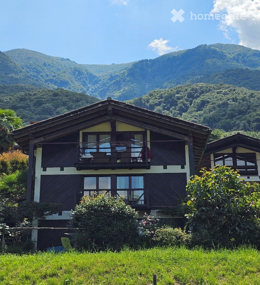 two story house, wooden and white exterior, large balcony, surrounded by nature