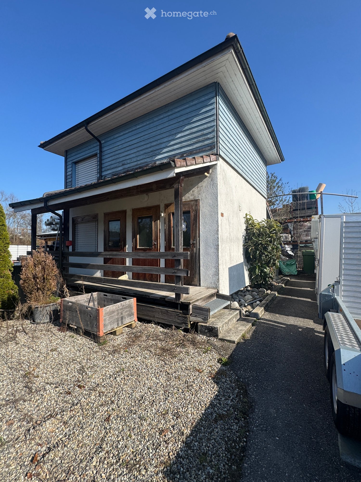 2 story house, blue exterior wall, red tile roof, white and brown interior, covered porch, gravel driveway