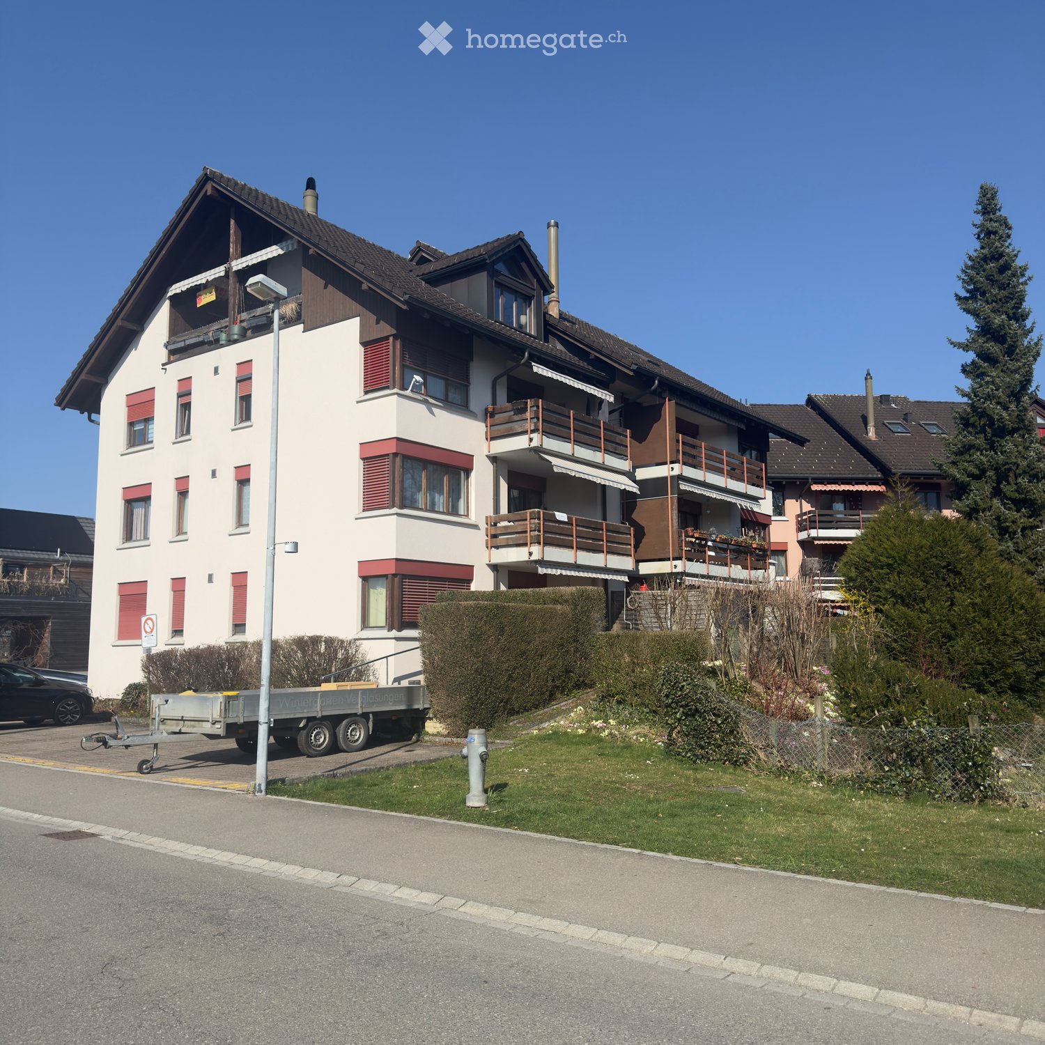3 story apartment building, white and brown exterior, red shutters, balconies, street view
