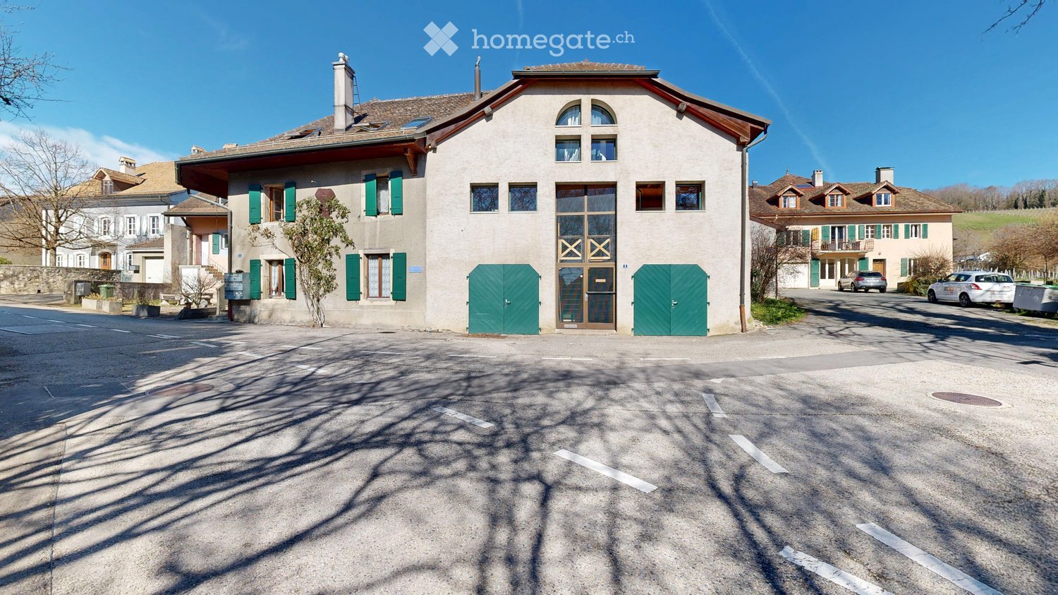2 story house, white walls, green shutters, 2 green doors, 2 cars parked in front