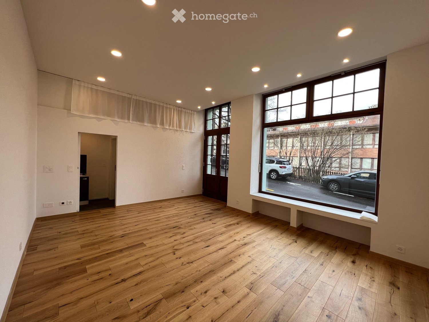 empty room, wooden floor, large windows, white walls, power outlets, door