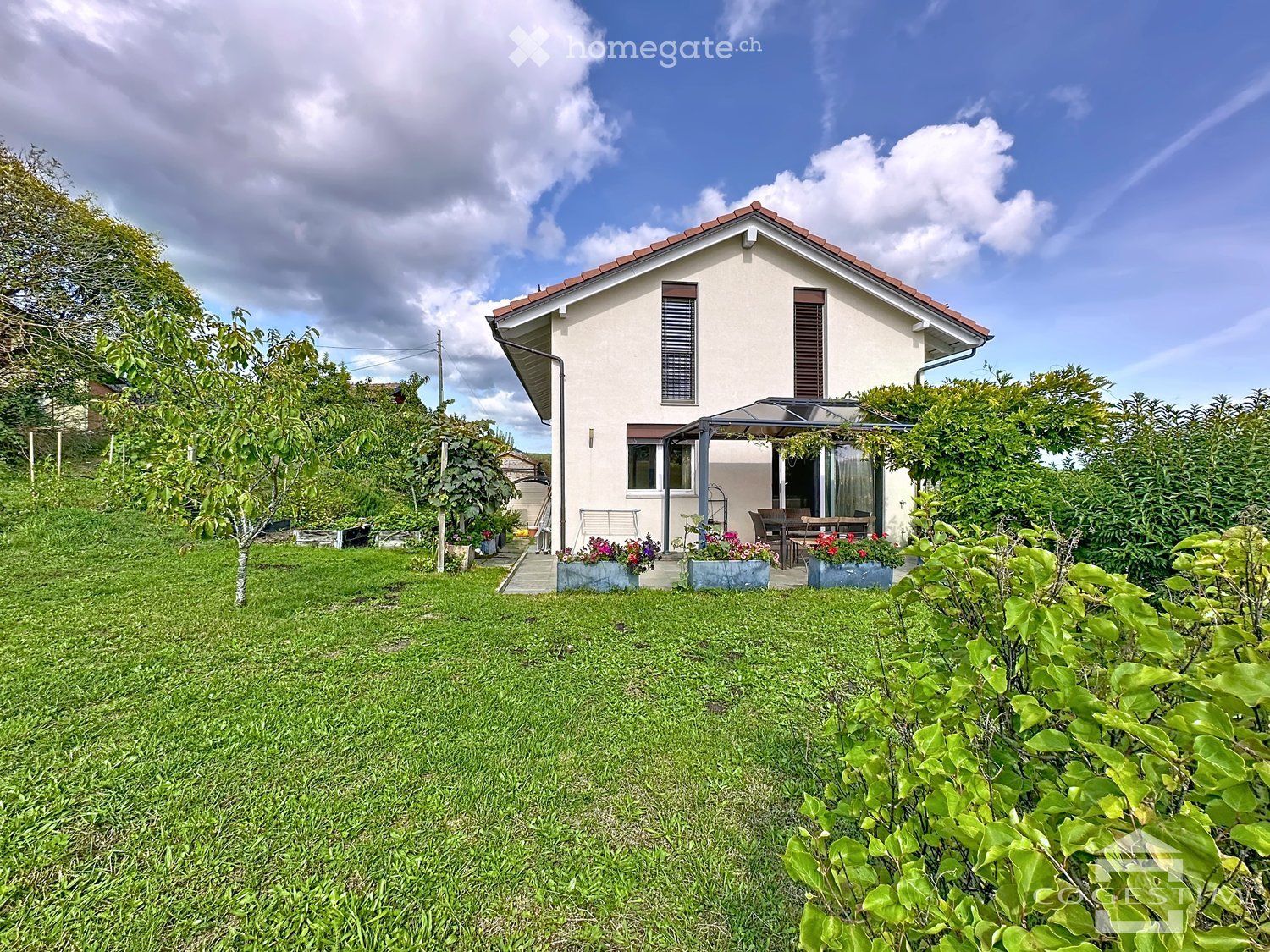 Detached house, white exterior, red roof, large windows, terrace, garden with flowers, green lawn