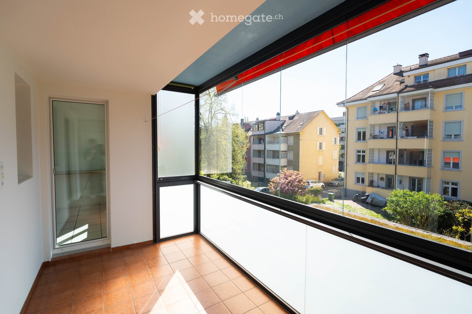large glass windows, tiled floor, balcony, view of buildings and trees
