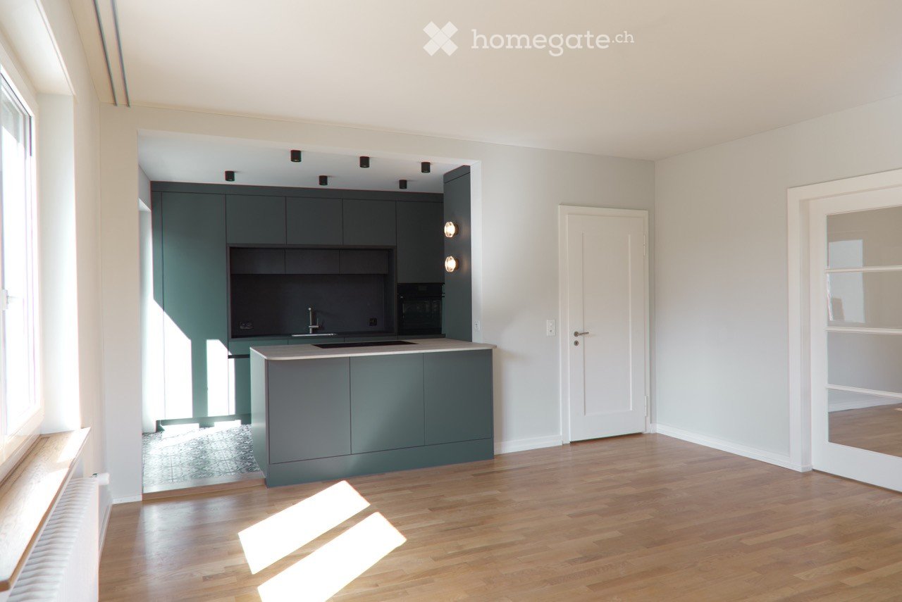 Modern kitchen with green cabinets, wooden floor, and white walls. Equipped with a sink, faucet, and microwave.