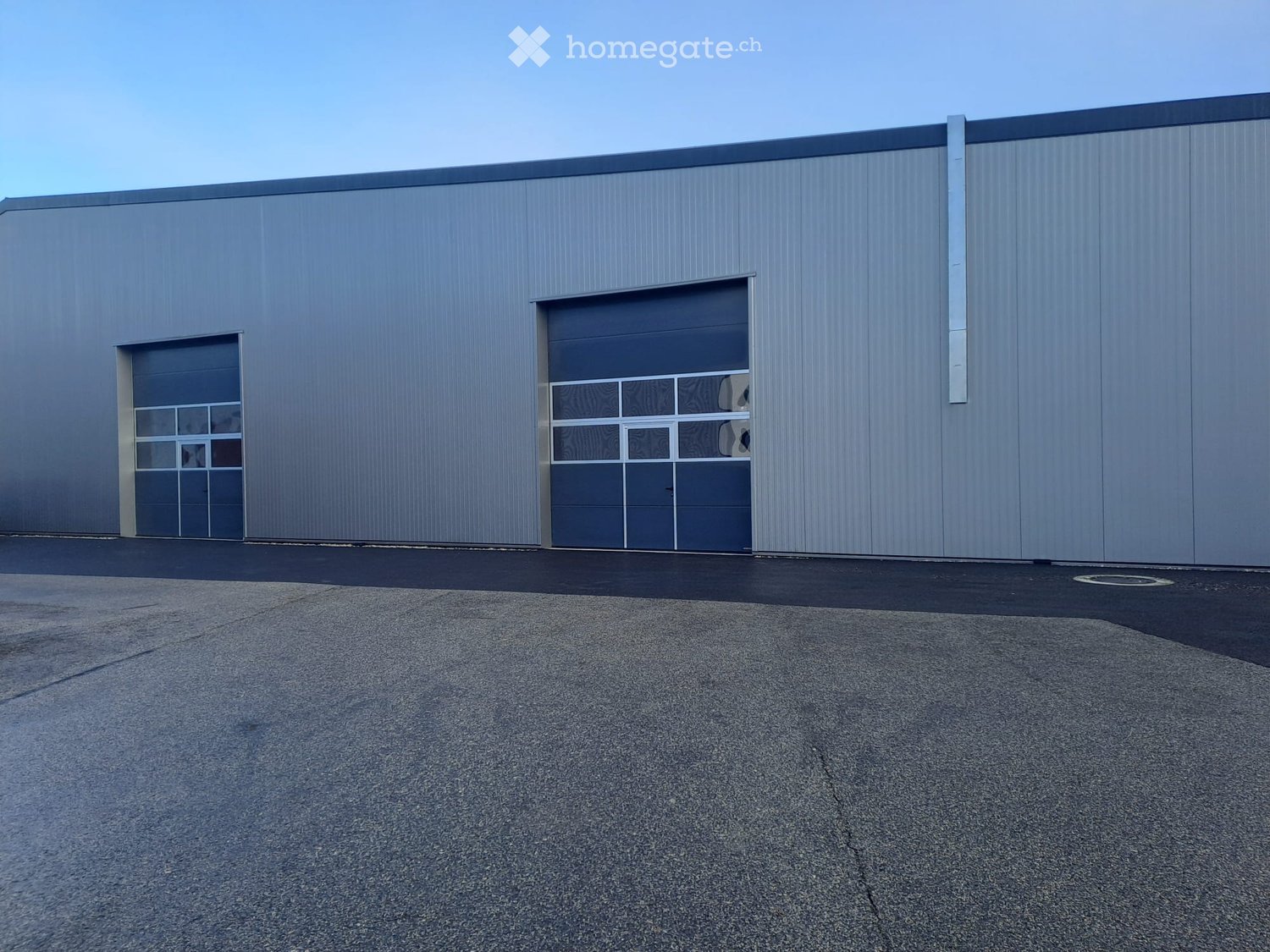 Modern industrial building with large garage doors and a smooth metal facade.