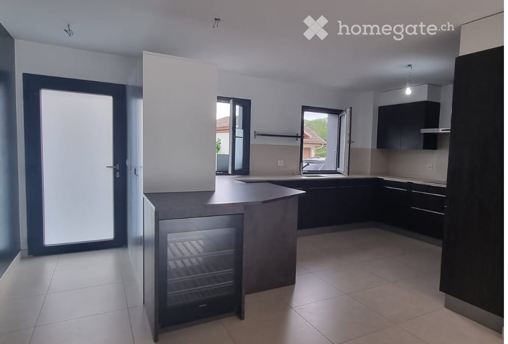 Modern kitchen with dark cabinets, a central island, and a built-in refrigerator. The space features large windows and a sleek, contemporary design.