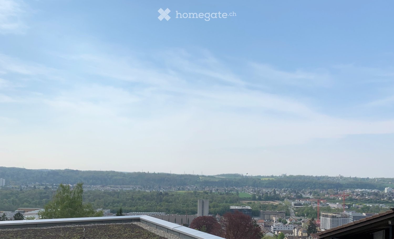 Balcony / Terrace. Panoramic cityscape view from a rooftop terrace, featuring a mix of residential and commercial buildings, green spaces, and distant hills under a partly cloudy sky.