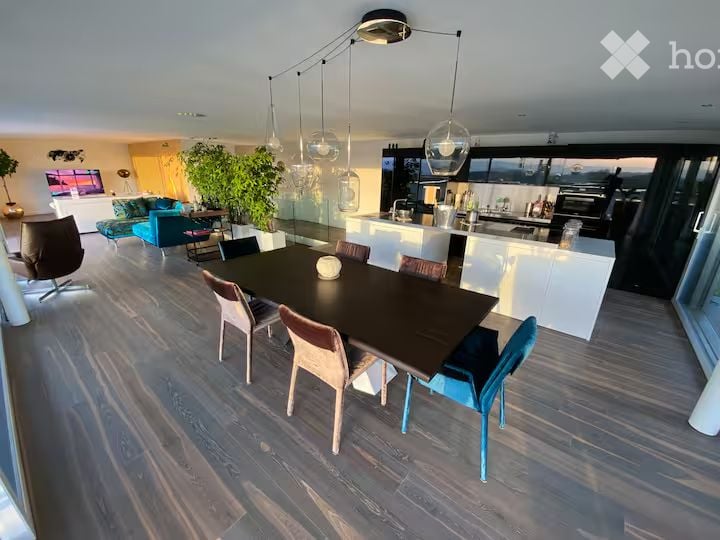 Furnished Room. Open-plan living and dining area with modern furniture, pendant lights, and a view through large windows.
