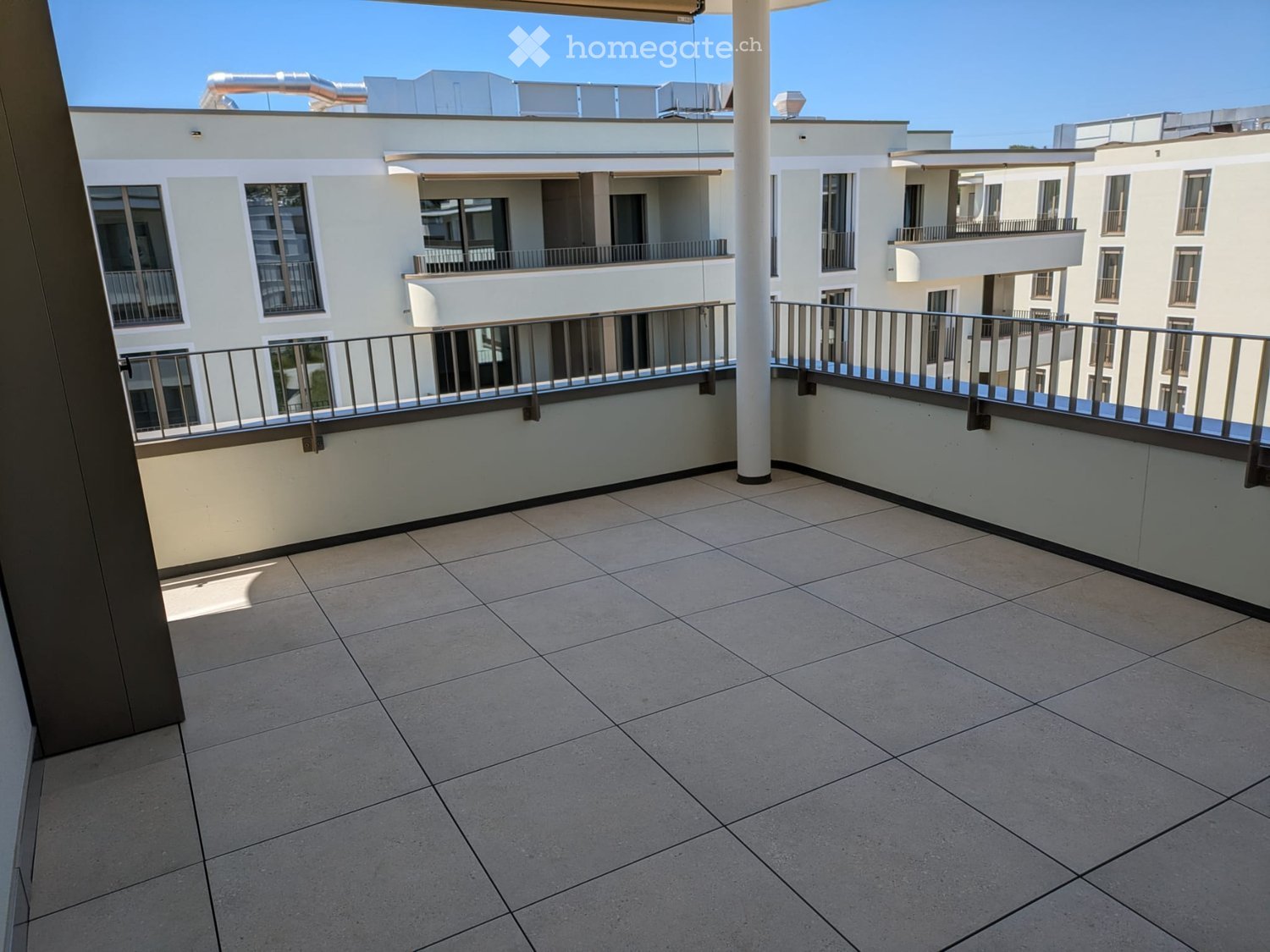Balcony with tiled floor, metal railing, and view of neighboring buildings.