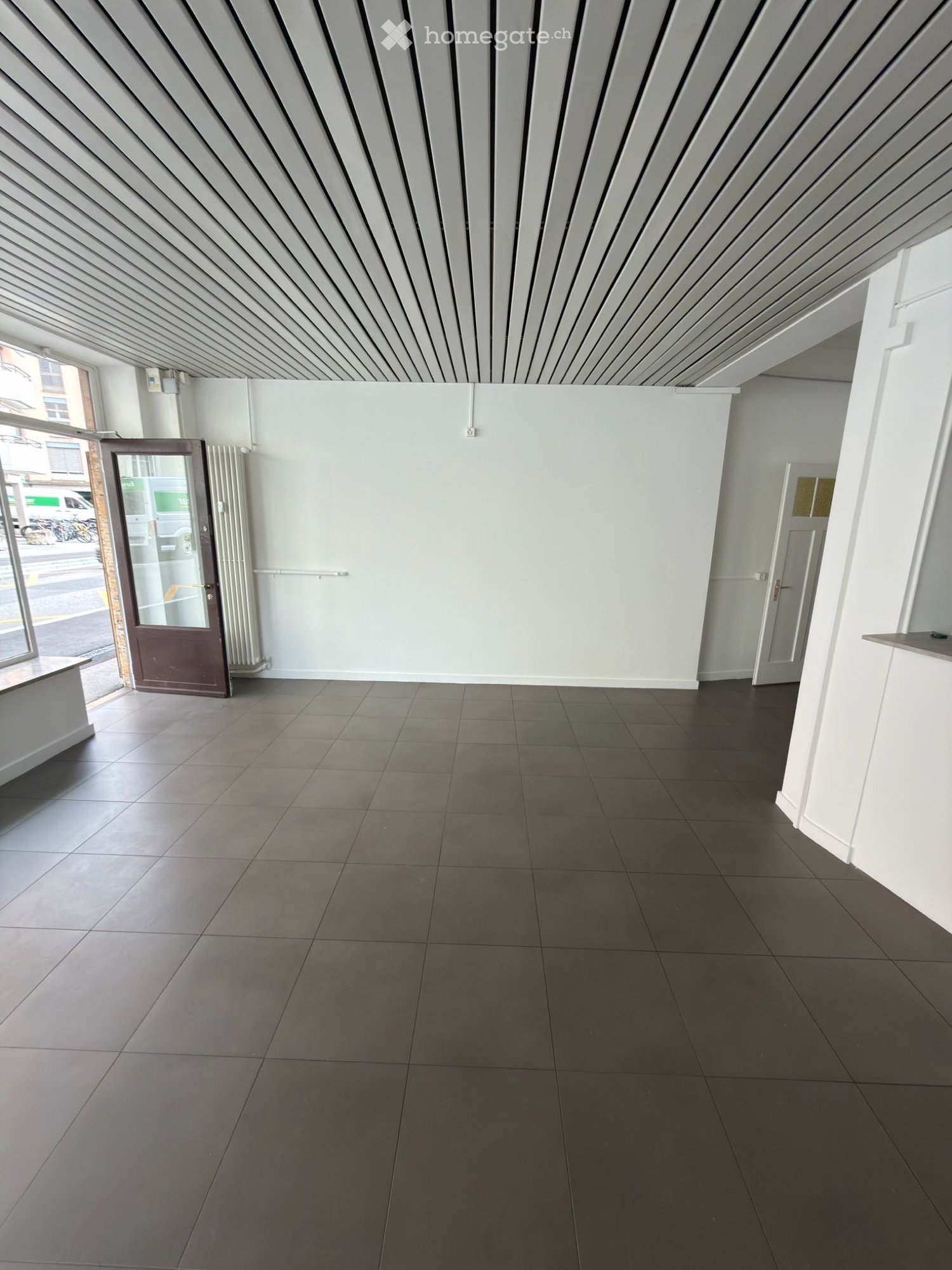 Empty room with tiled floor, white walls, and a door leading outside. No furniture or equipment visible.