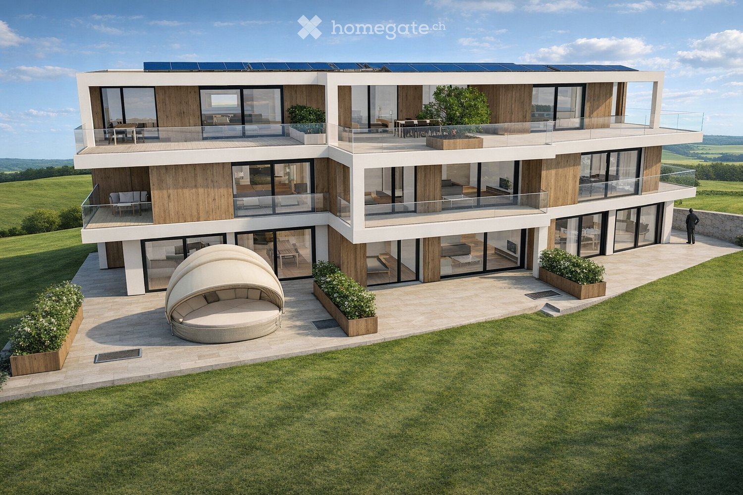 Modern two-story house with large windows, balconies, and solar panels on the roof. The house features a spacious outdoor seating area with a round lounge chair and planters.