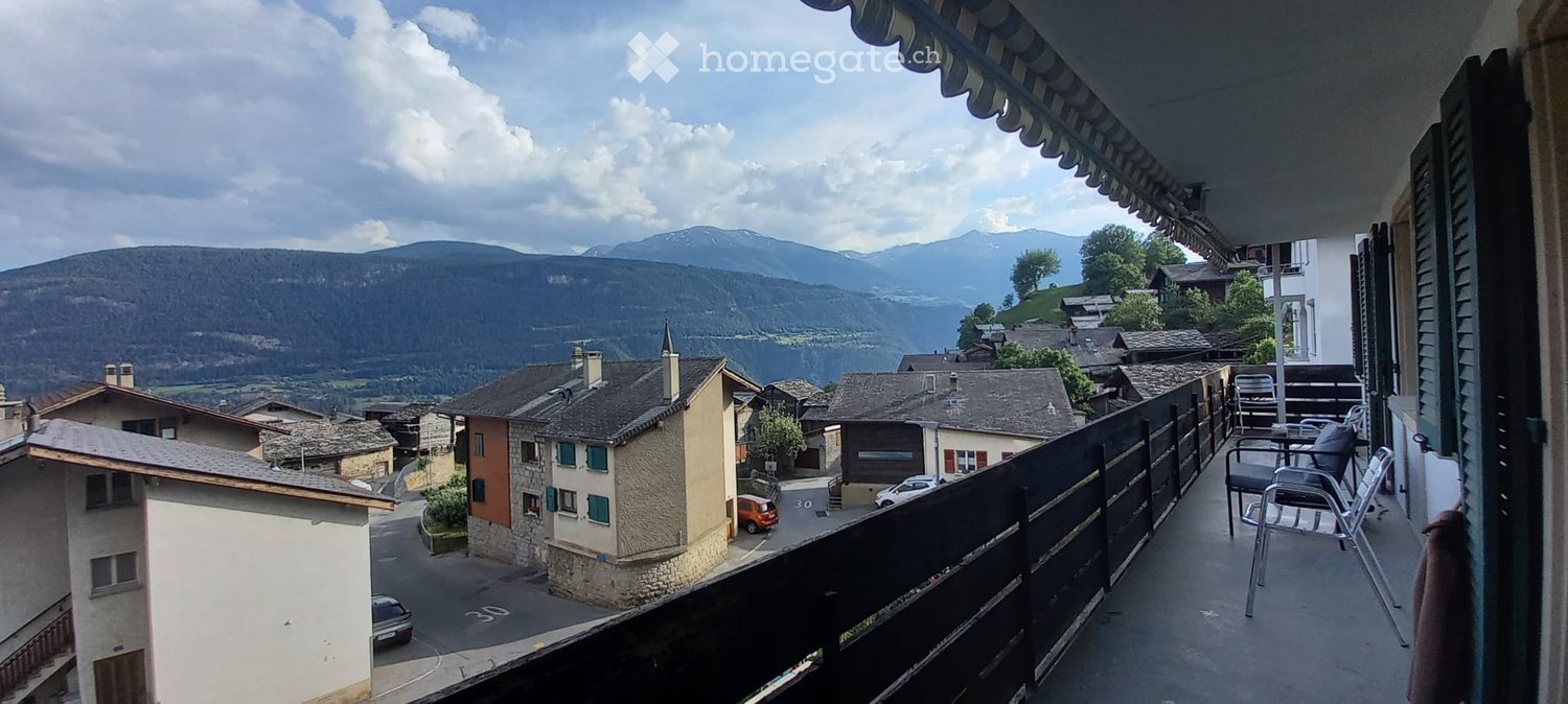 Balcony with a scenic mountain view, featuring a table and chairs.