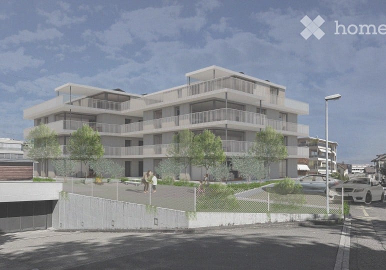 Modern multi-story residential building with balconies, surrounded by trees and a paved area with parked cars.
