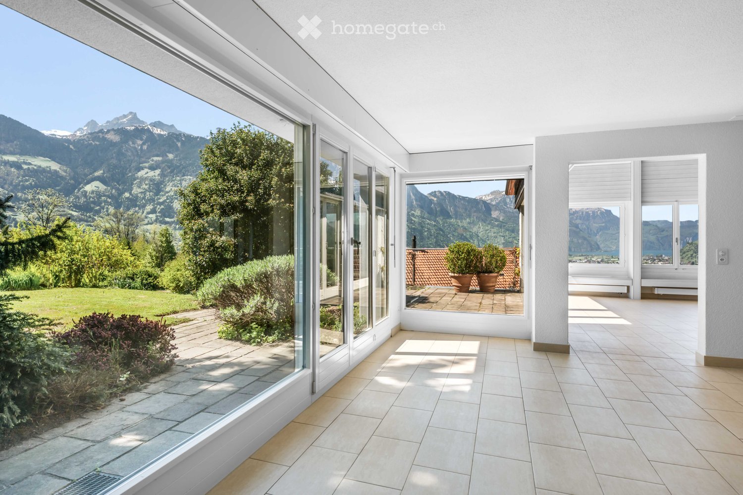 Bright, modern balcony with large glass doors, tiled flooring, and expansive mountain views.