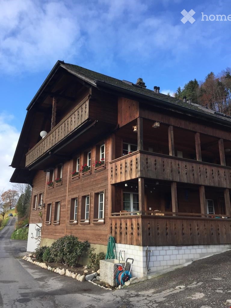 Traditional wooden house with multiple balconies, large windows, and flower boxes.