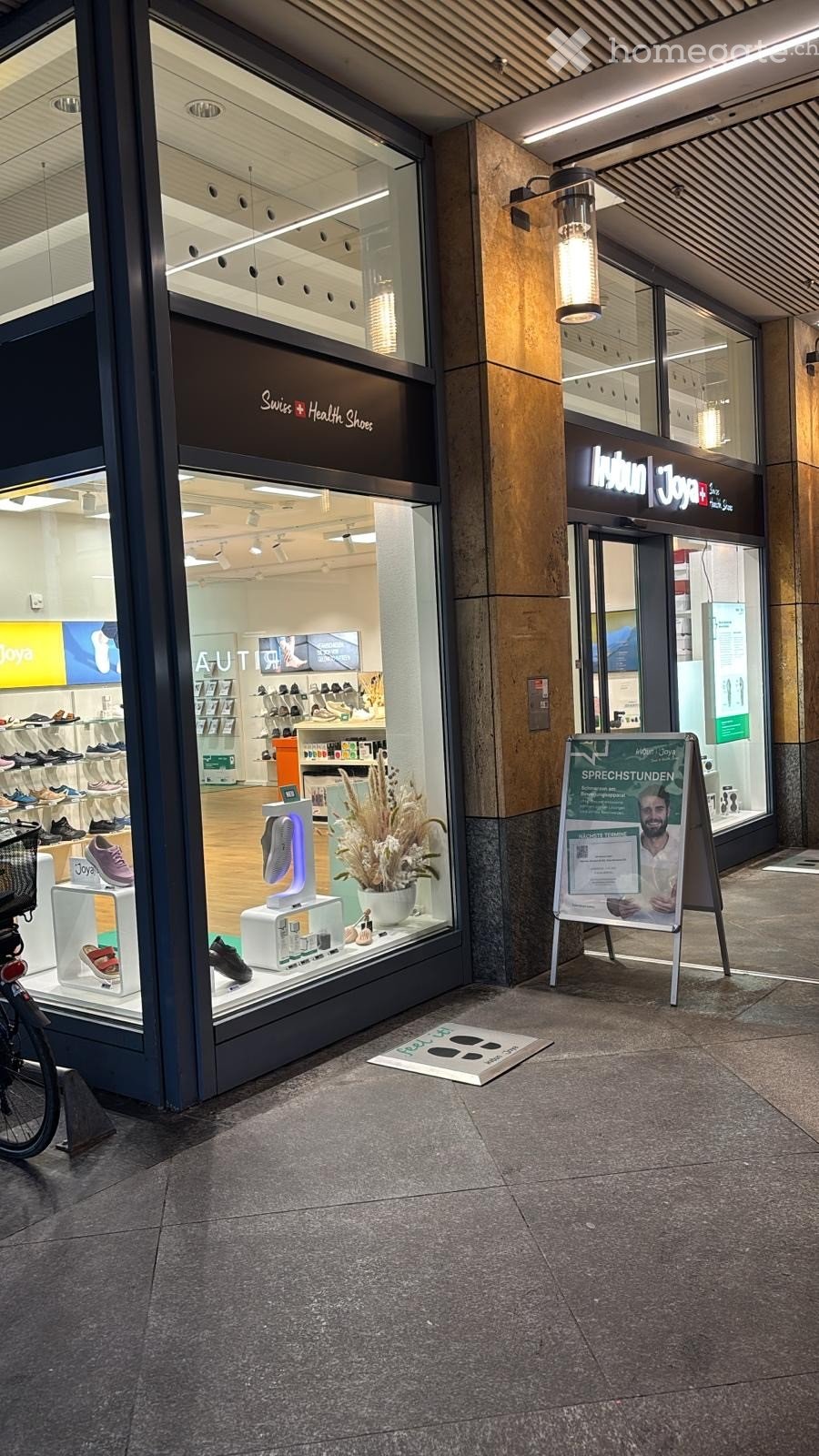 Store with glass door, wooden floor, display of shoes, flower vase, signboard with advertisement, and basket on the bicycle