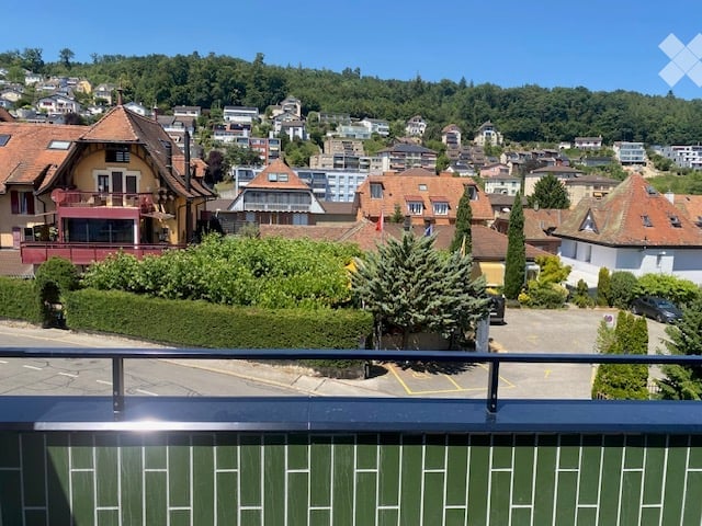 Balcony overlooking a town with houses, trees, and a clear blue sky.