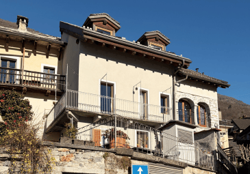 A multi-story stone building with balconies and arched windows, featuring a clear blue sky background.