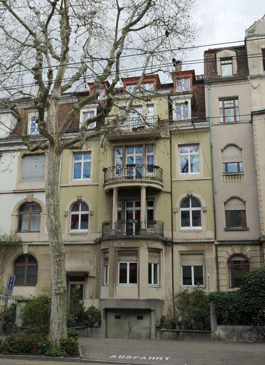 Multi-story residential building with balconies, large windows, and ornate architectural details.