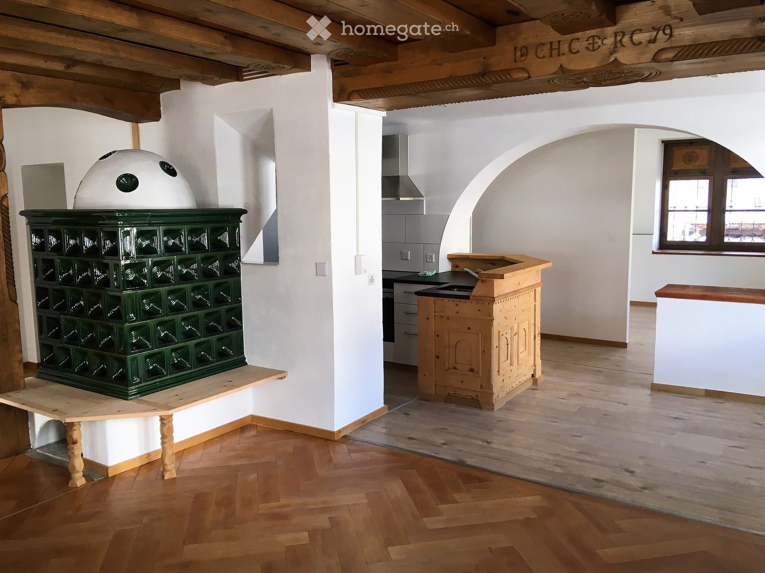 The kitchen features a wooden counter, sink, wooden cabinet, wooden table, wooden chair, and a wooden stove with a dome-shaped top.