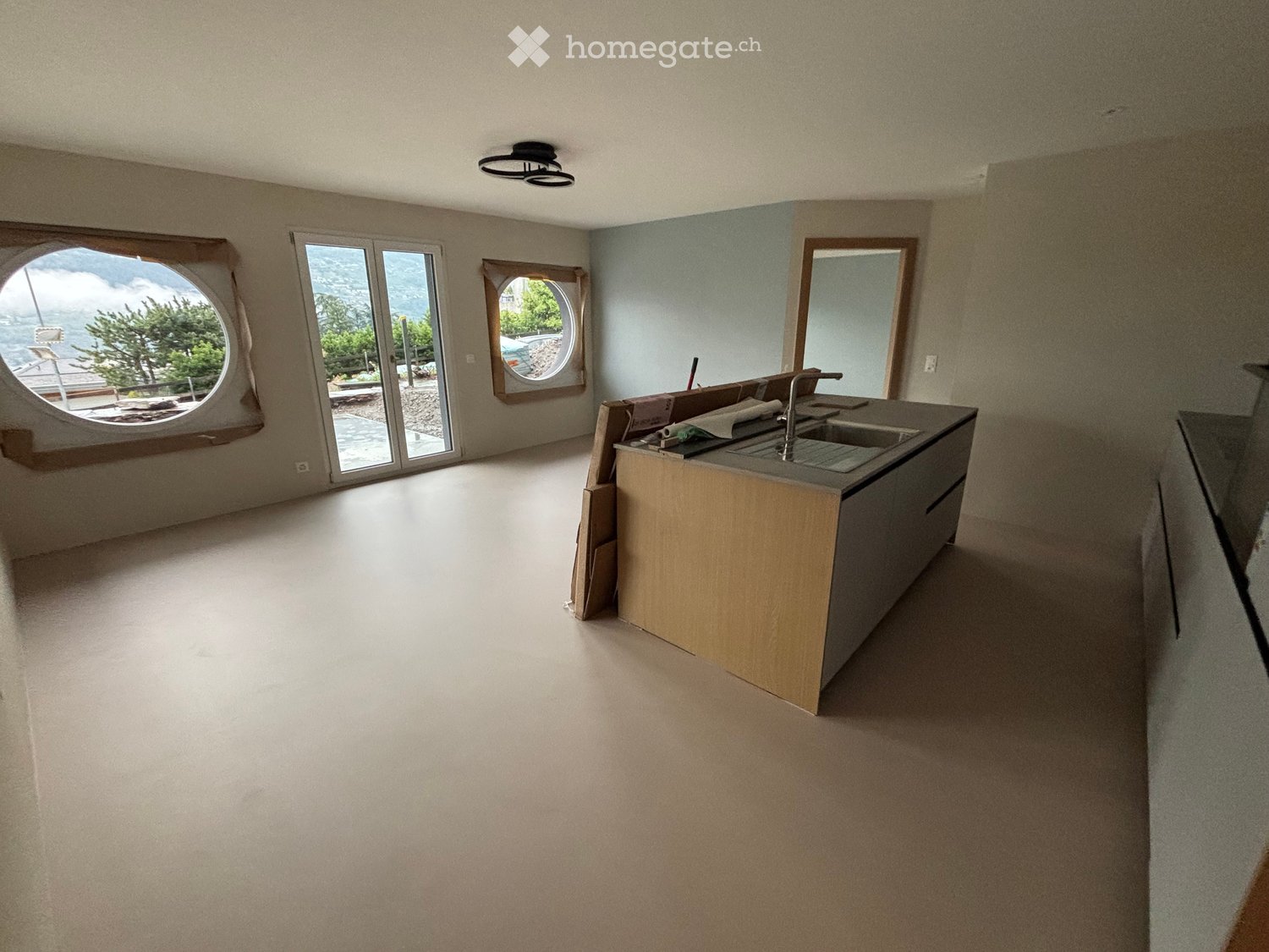 Empty kitchen with a countertop, sink, and large windows offering a scenic view of the outdoors.