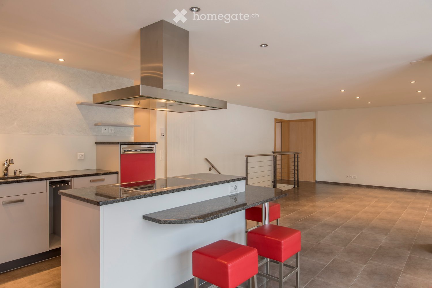 Modern kitchen with white cabinets, granite countertops, stainless steel range hood, and red stools at the island.