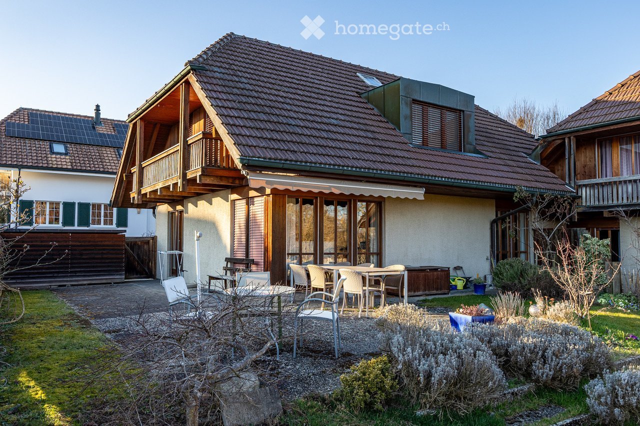 Detached house, brown roof, wooden balcony, solar panels, garden, outdoor dining area