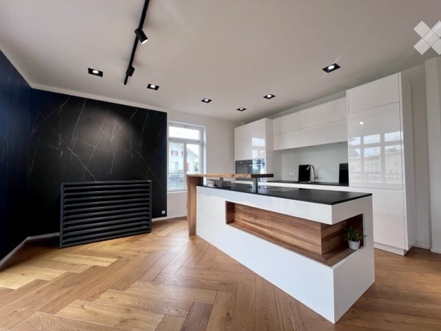 Modern kitchen with white cabinets, black countertops, wooden flooring, and built-in appliances.
