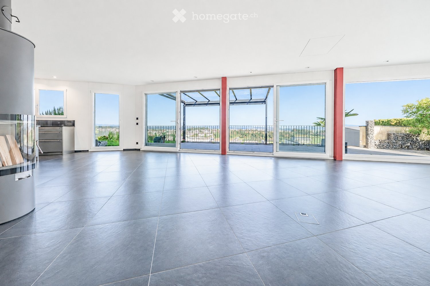 Empty room with large sliding glass doors leading to a balcony, polished tile floor, and modern white walls.