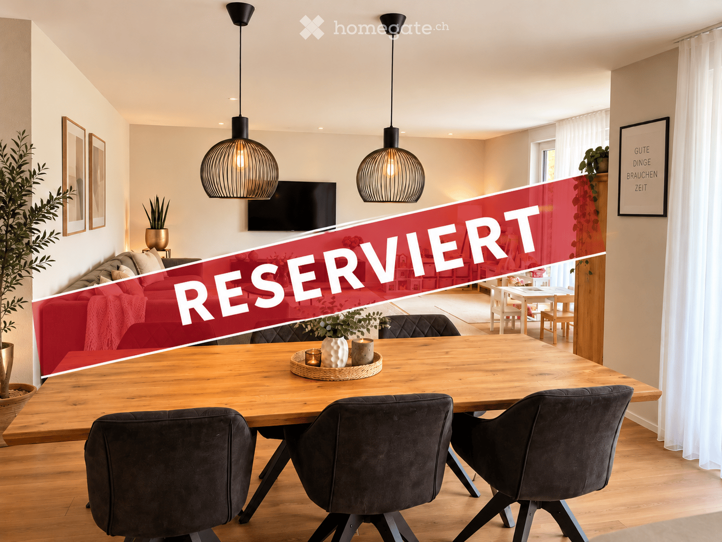 Modern living and dining area with a red sofa, wooden dining table, pendant lights, and a television mounted on the wall.