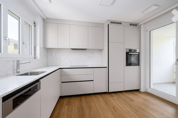 Modern kitchen with white cabinets, marble countertops, and wooden flooring. Features a sink, faucet, dishwasher, and oven.