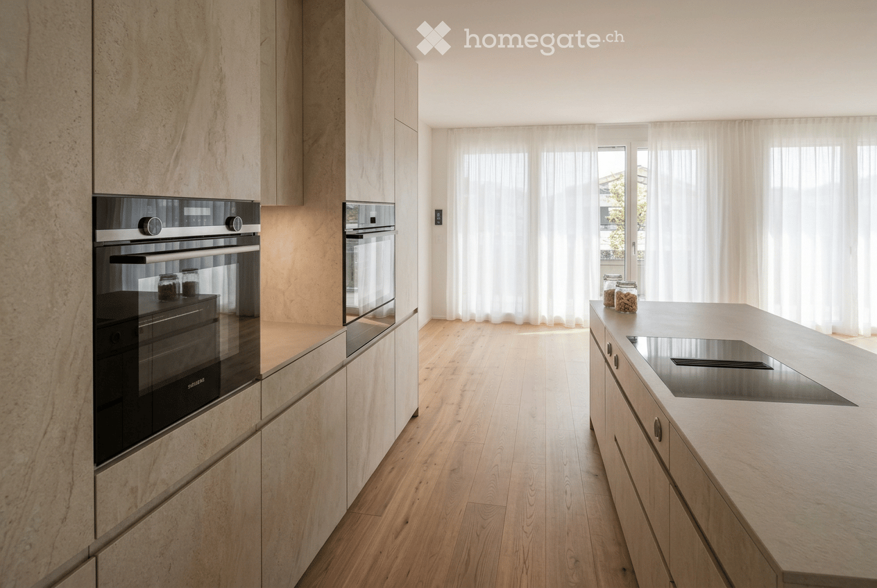 Modern kitchen with light wooden flooring, light-colored cabinets, stainless steel appliances, and a central island with a sink and countertop.