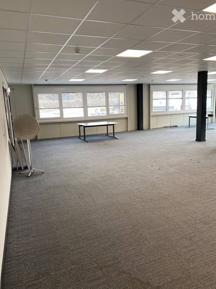 empty room, carpeted floor, two tables, windows with blinds, ceiling lights
