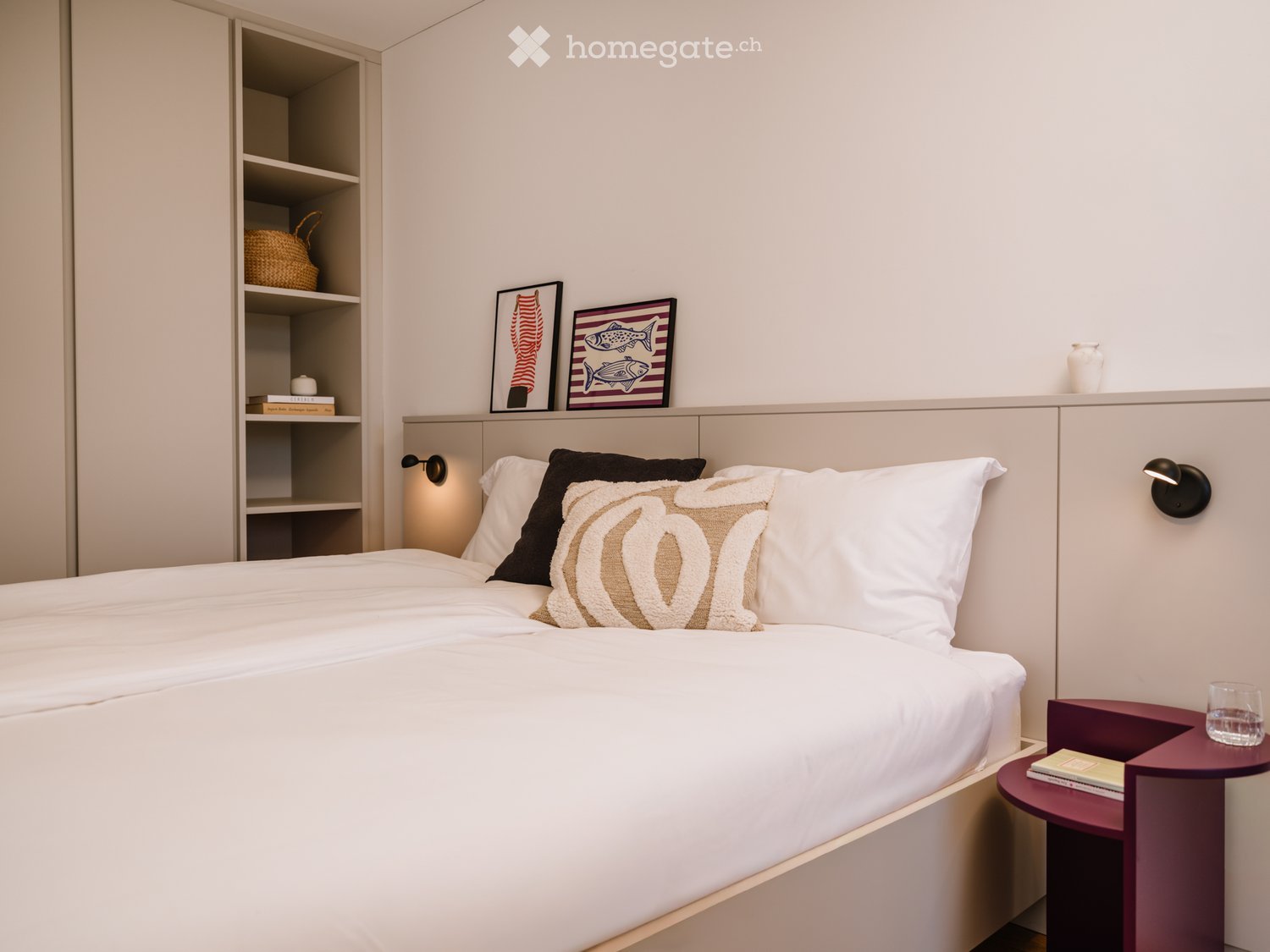 Modern bedroom with a neatly made bed, nightstand, and decorative items on shelves and walls.