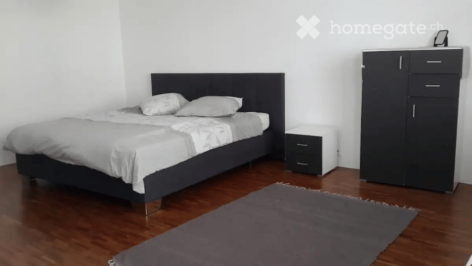 Modern bedroom with a dark wooden bed, white bedding, a nightstand, a wardrobe, and a grey rug on the floor.