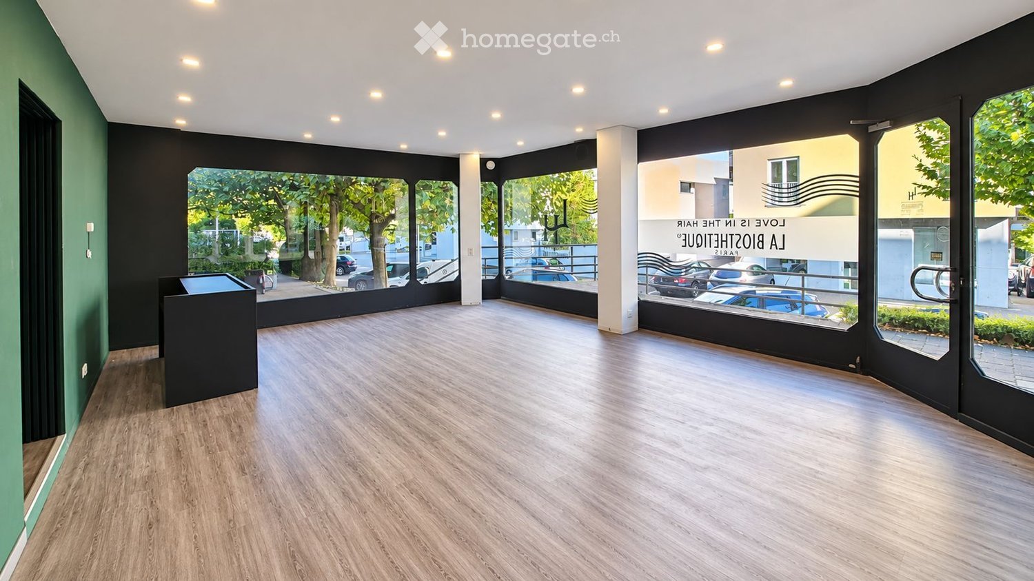 Empty room with wooden flooring, large windows, and modern lighting fixtures. No furniture or equipment present.