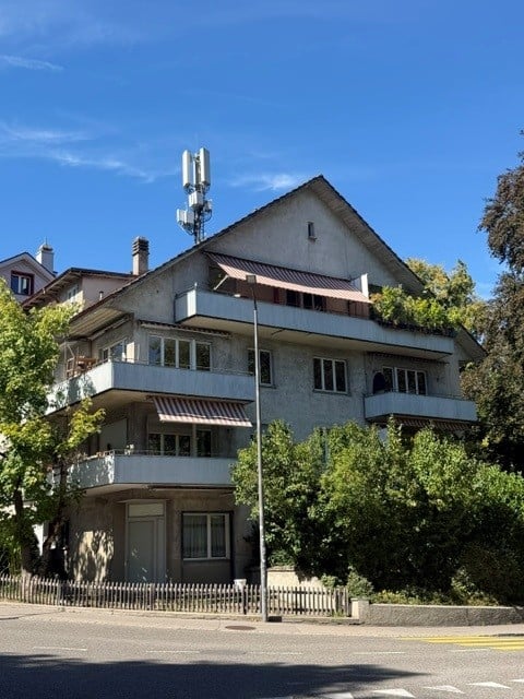 Multi-story residential building with balconies, large windows, and a modern design.