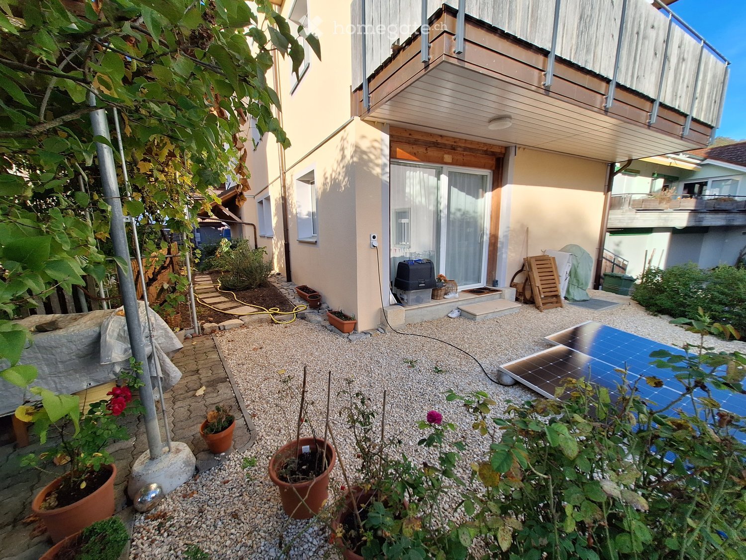 Garden area with gravel ground, potted plants, solar panel, and a covered outdoor seating area.
