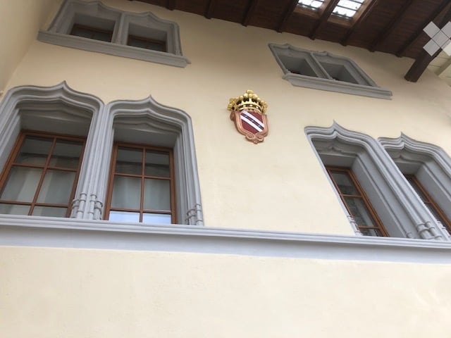 Facade with beige walls, three arched windows, and a coat of arms